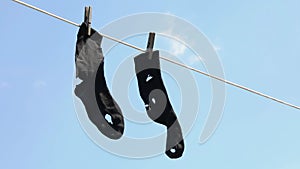 Leaky socks hang on a clothesline against the sky, a concept on the subject of poverty