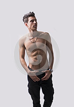 Lean athletic shirtless young man standing on light background