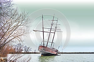 Leaning rusty shipwreck with tall masts marooned in cover near s