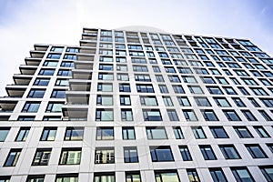 Leaning into the sky a modern high-rise residential building with rows of large windows and small corner balconies