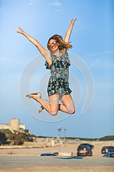 Leap of happiness. Joyful and smiling young woman jumps up with arms raised