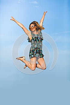 Leap of happiness. Joyful and smiling young woman jumps up with arms raised