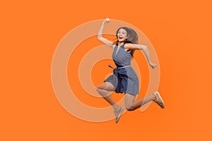 Leap to success. Full length of excited energetic motivated brunette woman in denim dress running in air