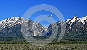 Lear Jet flying into Jackson Hole Airport next to the Grand Tetons Mountain Range in Wyoming