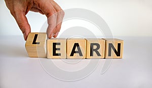 Learn or earn. Hand flips a cube and changes the word `earn` to `learn` or vice versa. Beautiful white background. Business