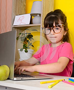 Learn English concept with kids, girl using her laptop. Kid using laptop watching online e-learning video