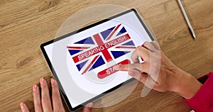 Learn english on tablet screen closeup. Student press start to learn to speak english on tablet