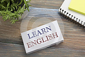 Learn English Text written on notebook page, red pencil and coffee cup. Office desk table top view