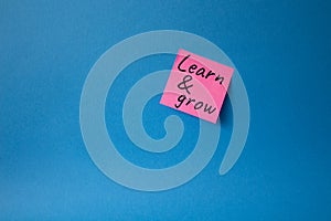 Learn and grow symbol. Concept words Learn and grow on pink steaky note. Beautiful blue background. Business and Learn and grow