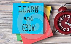 LEARN and GROW - words on note paper on wooden light background