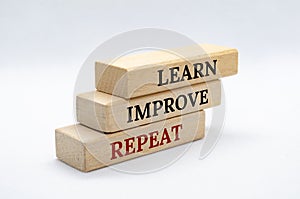 Learn, Improve and Repeat text on wooden blocks with white cover background. Improvement and development concept