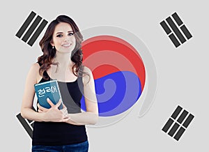 Learn korean language. Pretty young woman student with book against the South Korea flag background