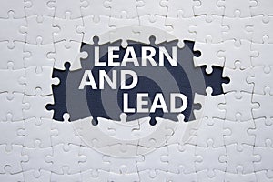 Learn and lead symbol. Concept words Learn and lead on white puzzle. Beautiful deep blue background. Business and Learn and lead