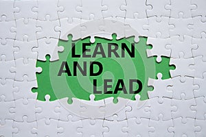 Learn and lead symbol. Concept words Learn and lead on white puzzle. Beautiful green background. Business and Learn and lead