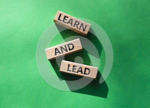 Learn and lead symbol. Concept words Learn and lead on wooden blocks. Beautiful green background. Business and Learn and lead