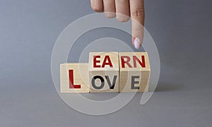 Learn and Love symbol. Businessman hand points at turned wooden cubes with words Love and Learn. Beautiful grey background.