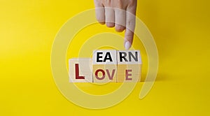 Learn and Love symbol. Businessman hand points at turned wooden cubes with words Love and Learn. Beautiful yellow background.