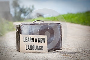 Learn a New Language. Old traveling suitcase on country road