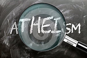 Learn, study and inspect atheism - pictured as a magnifying glass enlarging word atheism, symbolizes researching, exploring and