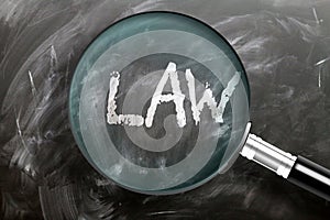 Learn, study and inspect law - pictured as a magnifying glass enlarging word law, symbolizes researching, exploring and analyzing