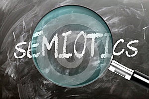 Learn, study and inspect Semiotics. A magnifying glass enlarging word \'semiotics\' written on a blackboard photo