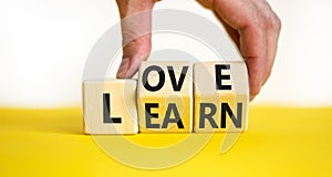 Learn to love symbol. Businessman turns wooden cubes and changes the concept word Love to Learn. Beautiful yellow table white