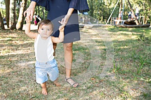 Learn to walk son child boy in mother hands in nature garden park