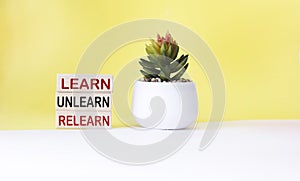 learn, unlearn, relearn - abstract words on wooden blocks with cactus flower and white and yellow background.Continuous learning, photo