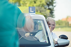 Learner driver girl with instructor learning how to drive car