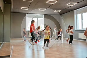 Learning dance figures with teacher. Group of little boys and girls dancing while having choreography class in the dance