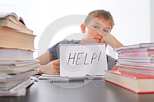 Learning difficulties, school, quarantine education concept. Tired frustrated boy sitting at table with many books. Word photo