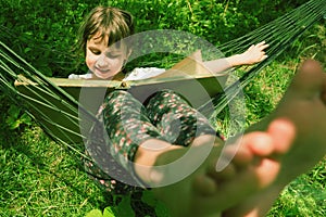 Learning always and everywher concept. Young beauutifuul girl reading book outdoors in hammock