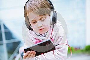 Learning is everywhere and anytime. Little cute child girl using mobile phone watching online e-learning video to studying english