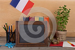 Learning french language concept - blank blackboard, flag of the France, books, pencils, compass