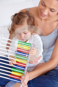 Learning at home. A baby girl and her mother playing with an abacus.