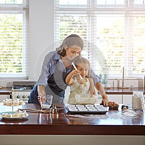 Learning how to bake with mom. a mother and her daughter baking in the kitchen.