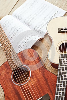 Learning how to play guitar. Vertical close up photo of acoustic and ukulele guitars lying on the wooden floor with