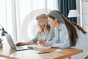 Learning how to use modern technologies. Smartphone and laptop. Mother and daughter is together at home