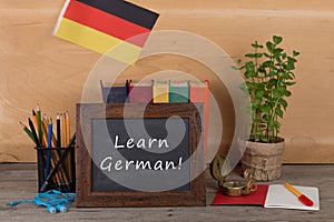 Learning languages concept - blackboard with text "Learn German", flag of the Germany, books, chancellery