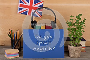 Learning languages concept - blue paper with text "Do you speak English?", flag of the Great Britain, headphones, books
