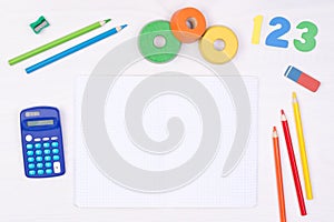 Learning maths. Kid`s desk with blank notebook, colorful pencils, numbers and a calculator