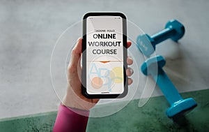 Learning Online Workout Concept. Young Woman using Mobile phone to choosing an Exercising Course. Dumbbell on the floor