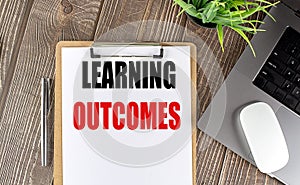 LEARNING OUTCOMES text on clipboard paper with laptop, mouse and pen