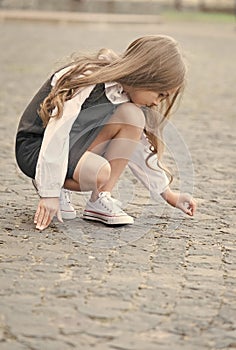 Learning before playing. Little child draw on pavement outdoors. Back to school fashion. Uniform dress. Early childhood