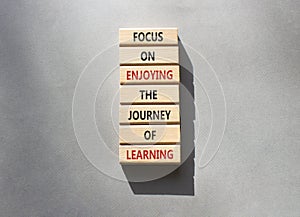 Learning symbol. Wooden blocks with words Focus on enjoying the journey of learning. Beautiful grey background. Business and Start