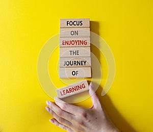 Learning symbol. Wooden blocks with words Focus on enjoying the journey of learning. Businessman hand. Beautiful yellow background