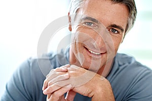 Learning to relax. Headshot portrait of a handsome mature man smiling while looking at the camera during the day.