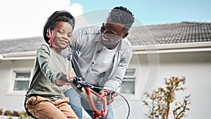 Learning to ride a bike with confidence. Portrait of an adorable boy learning to ride a bicycle with his father outdoors