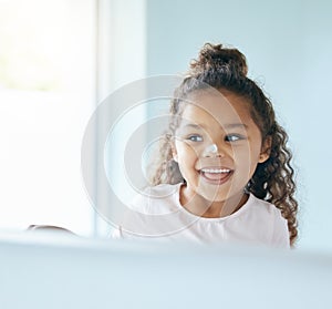 Learning to use sunscreen at a young age. Shot of a little girl applying lotion to her face in a bathroom at home.