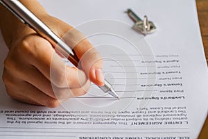 Lease agreement document concept. Landlord is signing the lease document paper with pen and key, Rental agreement form, signing ha